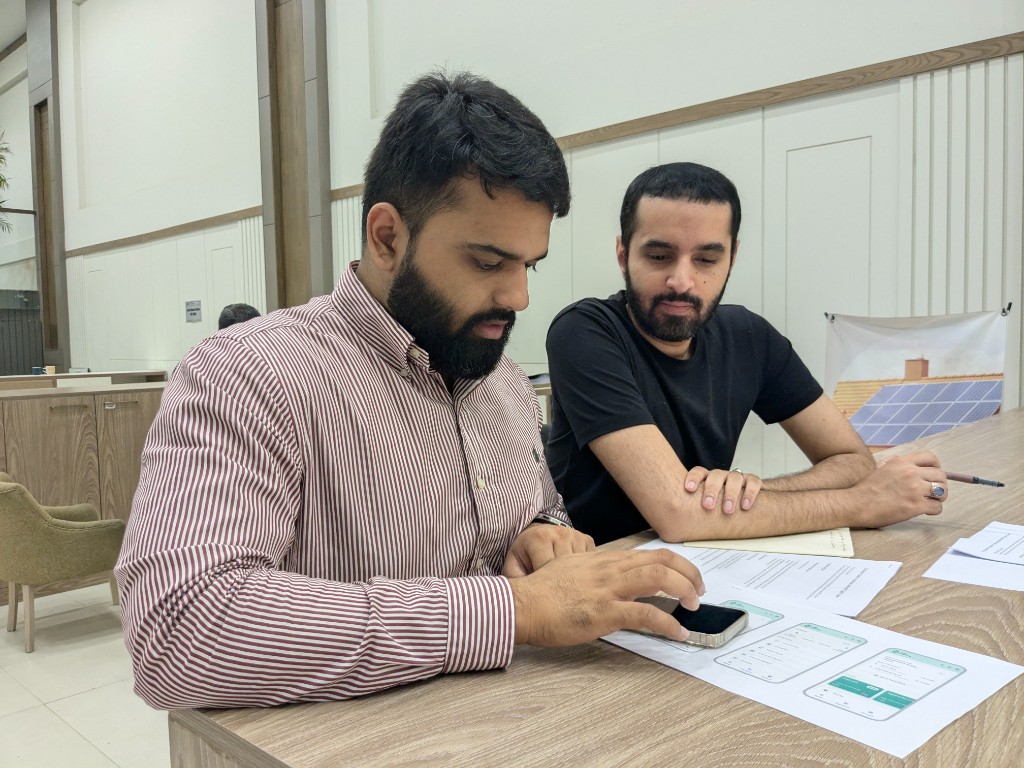 Branch staff reviewing printed NBP Digital app mockups during a field visit