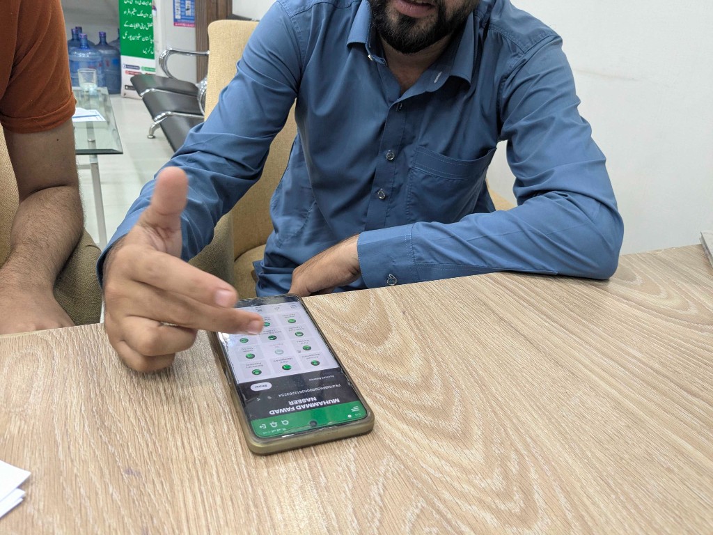Customer demonstrating the existing NBP Digital app on a phone during a branch visit